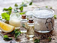 Verschiedene Gefäße mit Cremes und Gels und gesammelten Kräutern