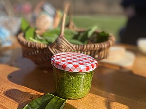 Glas mit Bärlauchpesto auf einem Tisch.