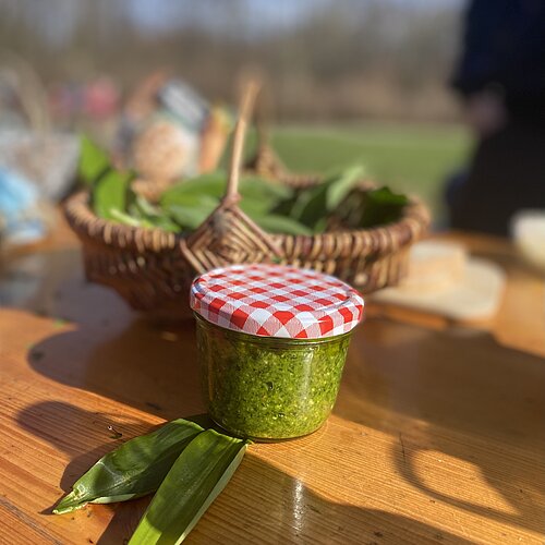 Glas mit Bärlauchpesto auf einem Tisch.